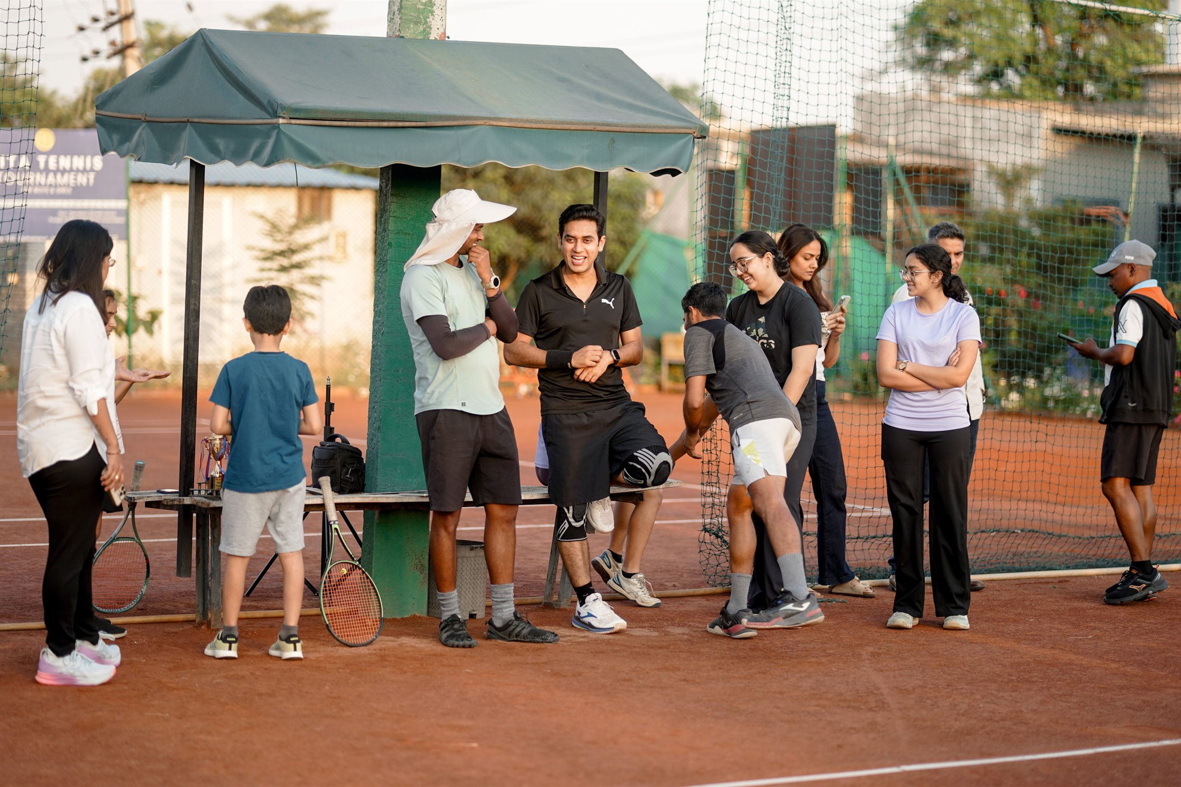 Players and coaches gathered beside a clay tennis court